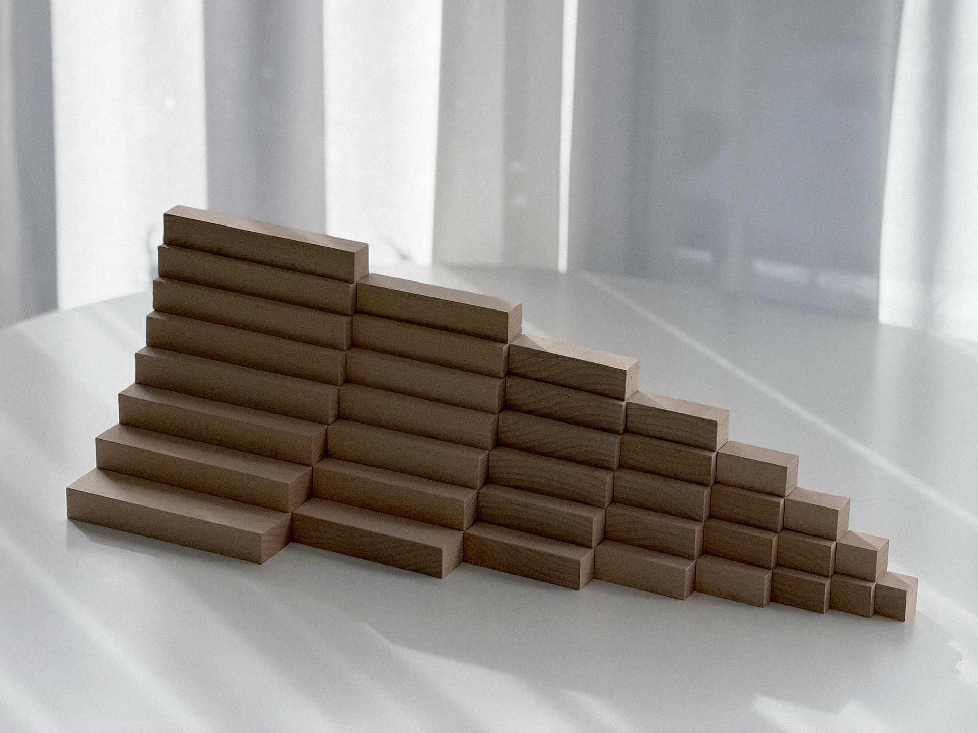 Low arrangement of rising wooden blocks in soft light.