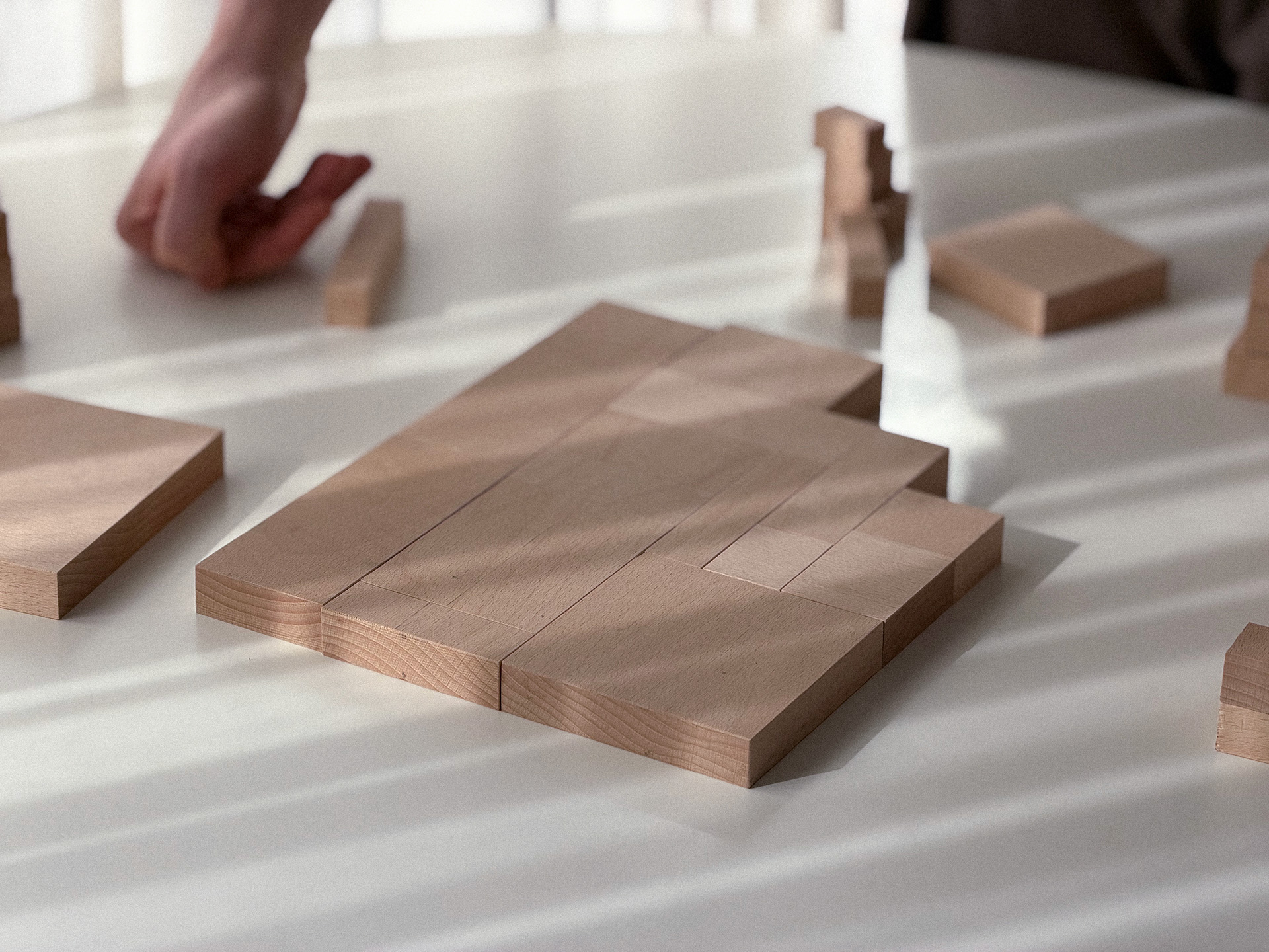 Hands arranging wooden forms across the table.